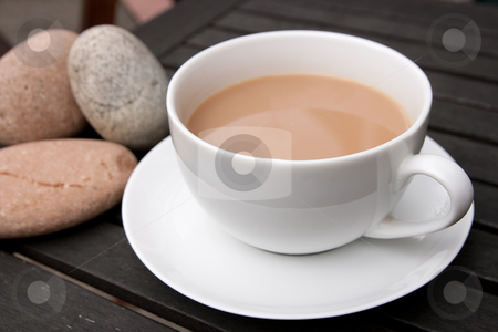 To use this stock image in your creative project, please select the size you need over to the right and click the "Add to Cart" button.
Your downloaded image will come with the Cutcaster watermark removed so don’t worry about the watermark you see on this page. Cup of Tea stock photo, Outdoor cup of tea in a white cup and saucer with stones on a wooden background by Keith Wilson