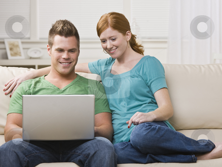 To use this stock image in your creative project, please select the size you need over to the right and click the "Add to Cart" button.
Your downloaded image will come with the Cutcaster watermark removed so don’t worry about the watermark you see on this page. Couple Viewing Laptop Together on the Couch stock photo, An attractive young couple sitting on a couch and viewing a laptop screen. They are smiling. Horizontally framed photo. by Jonathan Ross
