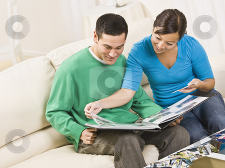 To use this stock image in your creative project, please select the size you need over to the right and click the "Add to Cart" button.
Your downloaded image will come with the Cutcaster watermark removed so don’t worry about the watermark you see on this page. Happy Couple Viewing Photo Album stock photo, An attractive and happy asian couple sitting together on a couch and viewing a photo album together. They are smiling. Horizontally framed shot. by Jonathan Ross