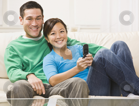 To use this stock image in your creative project, please select the size you need over to the right and click the "Add to Cart" button.
Your downloaded image will come with the Cutcaster watermark removed so don’t worry about the watermark you see on this page. Couple Watching Television stock photo, An attractive young couple sitting on a couch and watching television. They are smiling directly at the camera. The female is holding a remote. Horizontally framed photo. by Jonathan Ross