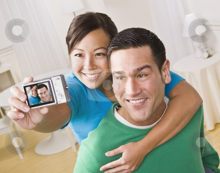 To use this stock image in your creative project, please select the size you need over to the right and click the "Add to Cart" button.
Your downloaded image will come with the Cutcaster watermark removed so don’t worry about the watermark you see on this page. Couple Taking a Self Portrait stock photo, An attractive young couple taking their own picture with a digital camera. They are smiling. The female is holding the camera. Horizontally framed shot. by Jonathan Ross