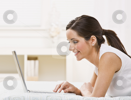 To use this stock image in your creative project, please select the size you need over to the right and click the "Add to Cart" button.
Your downloaded image will come with the Cutcaster watermark removed so don’t worry about the watermark you see on this page. Woman with Laptop stock photo, An attractive young woman lying on a bed and viewing a laptop screen. She is smiling. Horizontally framed shot. by Jonathan Ross