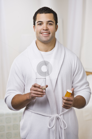 To use this stock image in your creative project, please select the size you need over to the right and click the "Add to Cart" button.
Your downloaded image will come with the Cutcaster watermark removed so don’t worry about the watermark you see on this page. Man Taking Pills stock photo, An attractive young man holding a prescription bottle and glass of water. He is wearing a bathrobe and is smiling at the camera. Vertically framed photo. by Jonathan Ross