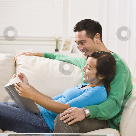 To use this stock image in your creative project, please select the size you need over to the right and click the "Add to Cart" button.
Your downloaded image will come with the Cutcaster watermark removed so don’t worry about the watermark you see on this page. Couple Reading Together stock photo, A young couple is seated together on their living room couch. They are reading a book together, smiling, and looking away from the camera. Square framed shot. by Jonathan Ross