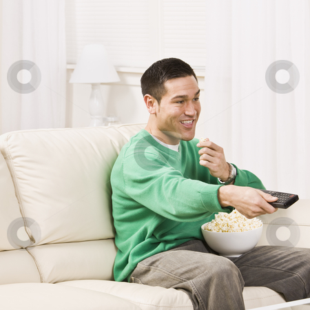 To use this stock image in your creative project, please select the size you need over to the right and click the "Add to Cart" button.
Your downloaded image will come with the Cutcaster watermark removed so don’t worry about the watermark you see on this page. Man Watching Television stock photo, A man seated on a couch and using a remote control for T.V. He is eating popcorn and smiling. Square framed photo. by Jonathan Ross
