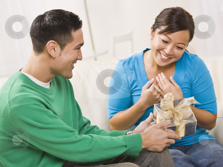 To use this stock image in your creative project, please select the size you need over to the right and click the "Add to Cart" button.
Your downloaded image will come with the Cutcaster watermark removed so don’t worry about the watermark you see on this page. Couple with Gift stock photo, An attractive young couple seated on a couch. The male is presenting a gift to the female. They are both smiling. Horizontally framed shot. by Jonathan Ross
