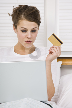 To use this stock image in your creative project, please select the size you need over to the right and click the "Add to Cart" button.
Your downloaded image will come with the Cutcaster watermark removed so don’t worry about the watermark you see on this page. Attractive Woman with Credit Card and Laptop stock photo, An attractive young woman holding a credit card and peering at a laptop screen. She is sitting in bed and has a contemplative expression. Vertically framed shot. by Jonathan Ross
