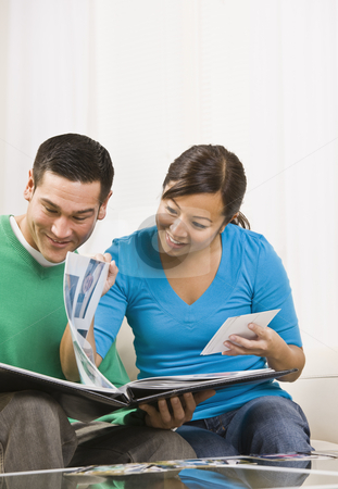 To use this stock image in your creative project, please select the size you need over to the right and click the "Add to Cart" button.
Your downloaded image will come with the Cutcaster watermark removed so don’t worry about the watermark you see on this page. Happy Couple Viewing Photos stock photo, An attractive young couple sitting on a couch and viewing a photo album together. They are smiling. Vertically framed shot. by Jonathan Ross