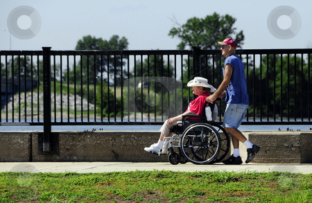 To use this stock image in your creative project, please select the size you need over to the right and click the "Add to Cart" button.
Your downloaded image will come with the Cutcaster watermark removed so don’t worry about the watermark you see on this page. Man pushing woman in wheelchair stock photo, Man pushing a woman in a wheelchair outdoors. by W. Paul Thomas