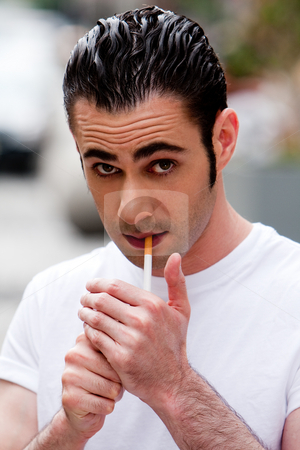 To use this stock image in your creative project, please select the size you need over to the right and click the "Add to Cart" button.
Your downloaded image will come with the Cutcaster watermark removed so don’t worry about the watermark you see on this page. Man lighting cigarette stock photo, Handsome Caucasian man wearing white shirt lighting a filter cigarette, on a blurred outdoor background by Paul Hakimata