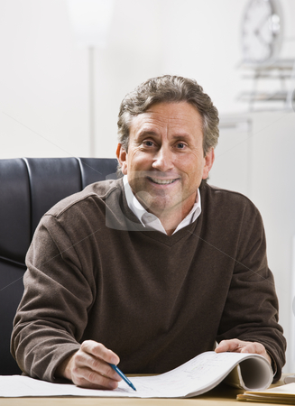 To use this stock image in your creative project, please select the size you need over to the right and click the "Add to Cart" button.
Your downloaded image will come with the Cutcaster watermark removed so don’t worry about the watermark you see on this page. Man in Office stock photo, A businessman is seated at a desk in an office and is smiling at the camera. Vertically framed shot. by Jonathan Ross