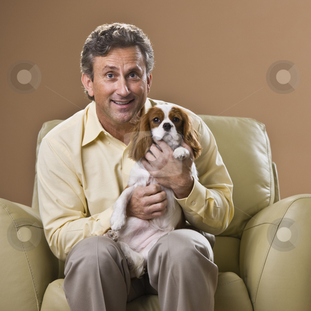 To use this stock image in your creative project, please select the size you need over to the right and click the "Add to Cart" button.
Your downloaded image will come with the Cutcaster watermark removed so don’t worry about the watermark you see on this page. Man with Puppy stock photo, A man is seated in a chair holding a puppy. He is smiling at the camera. Square framed shot. by Jonathan Ross