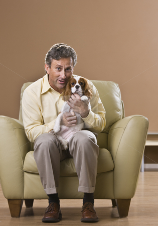 To use this stock image in your creative project, please select the size you need over to the right and click the "Add to Cart" button.
Your downloaded image will come with the Cutcaster watermark removed so don’t worry about the watermark you see on this page. Man Holding Puppy stock photo, A man is seated in a chair in a room and is holding a puppy. He is smiling at the camera. Vertically framed shot. by Jonathan Ross