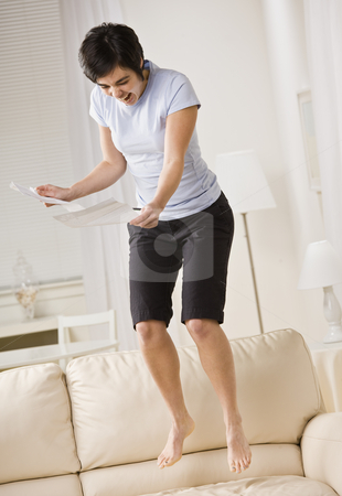 To use this stock image in your creative project, please select the size you need over to the right and click the "Add to Cart" button.
Your downloaded image will come with the Cutcaster watermark removed so don’t worry about the watermark you see on this page. Excited Woman Jumping on Couch stock photo, An excited young woman is reading a piece of paper and jumping up and down on the couch. She is looking away from the camera. Vertically framed shot. by Jonathan Ross
