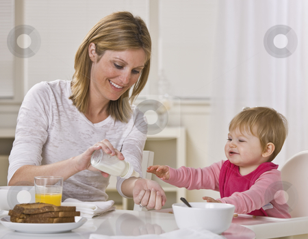 To use this stock image in your creative project, please select the size you need over to the right and click the "Add to Cart" button.
Your downloaded image will come with the Cutcaster watermark removed so don’t worry about the watermark you see on this page. Mother and Daughter Eating Breakfast stock photo, Smiling mother and baby daughter sit together at the breakfast table as the mother tests the temperature of the baby's bottle. Square framed shot. by Jonathan Ross