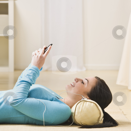 To use this stock image in your creative project, please select the size you need over to the right and click the "Add to Cart" button.
Your downloaded image will come with the Cutcaster watermark removed so don’t worry about the watermark you see on this page. Woman With MP3 Player stock photo, A young woman is lying on the floor and listening to an mp3 player. She is smiling and looking away from the camera. Square framed shot. by Jonathan Ross