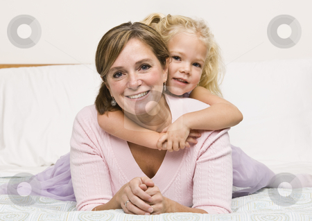 To use this stock image in your creative project, please select the size you need over to the right and click the "Add to Cart" button.
Your downloaded image will come with the Cutcaster watermark removed so don’t worry about the watermark you see on this page. Mother and Daughter Cuddling on Bed stock photo, A mother is lying with her daughter on her bed. The girl has her arms aroung her mother and they are smiling at the camera. Horizontally framed shot. by Jonathan Ross
