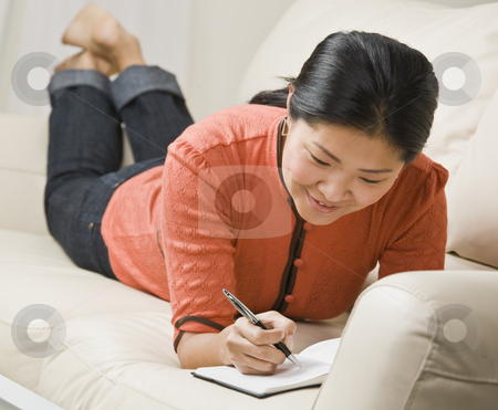To use this stock image in your creative project, please select the size you need over to the right and click the "Add to Cart" button.
Your downloaded image will come with the Cutcaster watermark removed so don’t worry about the watermark you see on this page. Woman Writing in Book stock photo, A woman is laying on the couch and writing in a book. She is smiling and looking away from the camera. Horizontally framed shot. by Jonathan Ross