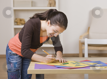 To use this stock image in your creative project, please select the size you need over to the right and click the "Add to Cart" button.
Your downloaded image will come with the Cutcaster watermark removed so don’t worry about the watermark you see on this page. Girl Working on Project stock photo, A young girl is working on a project. She is smiling and looking down at her work. Square framed shot. by Jonathan Ross