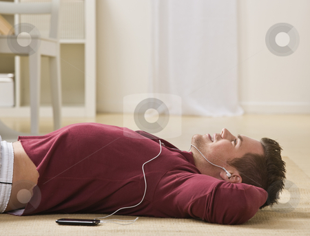 To use this stock image in your creative project, please select the size you need over to the right and click the "Add to Cart" button.
Your downloaded image will come with the Cutcaster watermark removed so don’t worry about the watermark you see on this page. Man Listening to Music stock photo, A man is lying on the floor and listening to his mp3 player. He is looking away from the camera. Horizontally framed shot. by Jonathan Ross