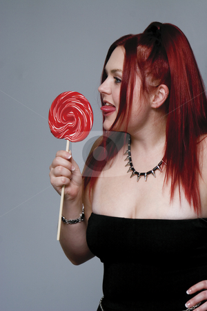 To use this stock image in your creative project, please select the size you need over to the right and click the "Add to Cart" button.
Your downloaded image will come with the Cutcaster watermark removed so don’t worry about the watermark you see on this page. Red hair goth model with lollipop stock photo, Red hair female model in goth look bitting on big red lollipop by Yann Poirier