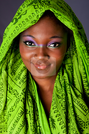 To use this stock image in your creative project, please select the size you need over to the right and click the "Add to Cart" button.
Your downloaded image will come with the Cutcaster watermark removed so don’t worry about the watermark you see on this page. Smiling African woman with headwrap stock photo, The face of an innocent smiling beautiful young African-American woman with green headwrap and purple-green makeup, isolated by Paul Hakimata