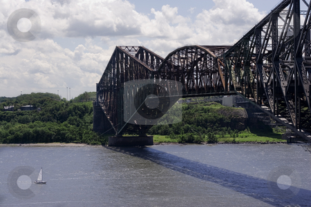 To use this stock image in your creative project, please select the size you need over to the right and click the "Add to Cart" button.
Your downloaded image will come with the Cutcaster watermark removed so don’t worry about the watermark you see on this page. Metal bridge stock photo, Quebec old metal bridge with sail boat passing under by Yann Poirier