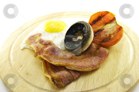 To use this stock image in your creative project, please select the size you need over to the right and click the "Add to Cart" button.
Your downloaded image will come with the Cutcaster watermark removed so don’t worry about the watermark you see on this page. Breakfast on a Wooden Plate stock photo, Slices of crispy pork bacon with half a grilled tomato a fried egg and a mushroom on a wooden round plate with a white background by Keith Wilson