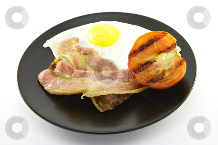 To use this stock image in your creative project, please select the size you need over to the right and click the "Add to Cart" button.
Your downloaded image will come with the Cutcaster watermark removed so don’t worry about the watermark you see on this page. Bacon, Eggs and Tomato on a Black Plate stock photo, Slices of crispy pork bacon with half a grilled tomato and a fried egg on a black round plate with a white background by Keith Wilson