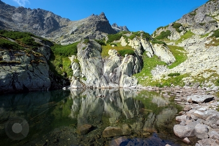 To use this stock image in your creative project, please select the size you need over to the right and click the "Add to Cart" button.
Your downloaded image will come with the Cutcaster watermark removed so don’t worry about the watermark you see on this page. Peak reflecting in a mountain lake stock photo, Stone wall of a peak reflecting in waters of a mountain lake by Juraj Kovacik