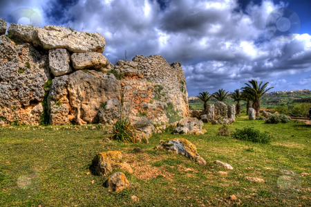 To use this stock image in your creative project, please select the size you need over to the right and click the "Add to Cart" button.
Your downloaded image will come with the Cutcaster watermark removed so don’t worry about the watermark you see on this page. Ggantija Temple Remains in Gozo stock photo, An image of the 7000 year old ancient ruins of Ggantija in Gozo. Palm trees can be seen in the background and there are many clouds in the sky. by Stephen Kiernan