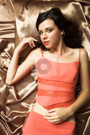 To use this stock image in your creative project, please select the size you need over to the right and click the "Add to Cart" button.
Your downloaded image will come with the Cutcaster watermark removed so don’t worry about the watermark you see on this page. Young brunette woman stock photo, Young adult brunette woman with pink evening dress and long brown curly hair and brown eyes lying on silk sheets by Sean Nel