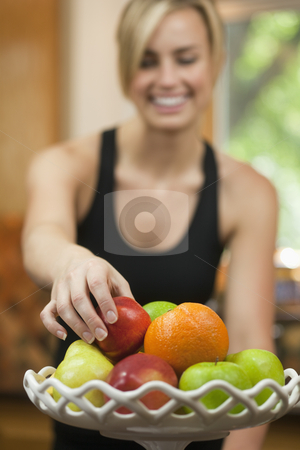 To use this stock image in your creative project, please select the size you need over to the right and click the "Add to Cart" button.
Your downloaded image will come with the Cutcaster watermark removed so don’t worry about the watermark you see on this page. Woman Eating Fruit stock photo, A young woman is picking up a piece of fruit, smiling, and looking away from the camera. Vertically framed shot. by Edward Bock