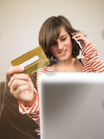 To use this stock image in your creative project, please select the size you need over to the right and click the "Add to Cart" button.
Your downloaded image will come with the Cutcaster watermark removed so don’t worry about the watermark you see on this page. Young Woman Shopping via Phone stock photo, A young woman sits in front of a laptop, holding her credit card and talking on the phone. Vertical format. by Mog Ddl