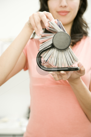 To use this stock image in your creative project, please select the size you need over to the right and click the "Add to Cart" button.
Your downloaded image will come with the Cutcaster watermark removed so don’t worry about the watermark you see on this page. Young Woman with Rotary Card File stock photo, Close-up cropped image of young woman holding rotary card file. She is smiling, facing the camera, and viewable from the nose to the waist. Vertically framed shot. by Paul Burns