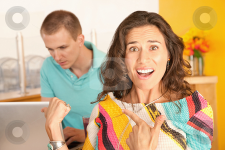 To use this stock image in your creative project, please select the size you need over to the right and click the "Add to Cart" button.
Your downloaded image will come with the Cutcaster watermark removed so don’t worry about the watermark you see on this page. Angry Couple stock photo, Image of a woman in the foreground with a frustrated expression is pointing to a man in the background using a laptop. Horizontal shot. by Scott Griessel