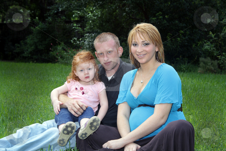 To use this stock image in your creative project, please select the size you need over to the right and click the "Add to Cart" button.
Your downloaded image will come with the Cutcaster watermark removed so don’t worry about the watermark you see on this page. Family Outdoors stock photo, A father, mother, and daughter sitting in the grass. The mother is approximately 26 weeks pregnant. by Carl Stewart
