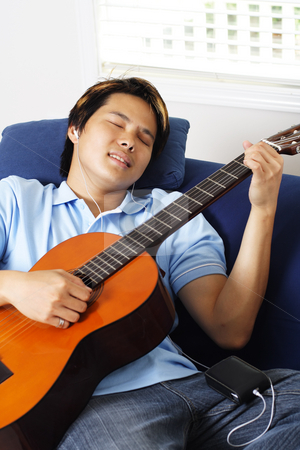 To use this stock image in your creative project, please select the size you need over to the right and click the "Add to Cart" button.
Your downloaded image will come with the Cutcaster watermark removed so don’t worry about the watermark you see on this page. Guitar player stock photo, Young man relaxing at home by playing guitar by Suprijono Suharjoto