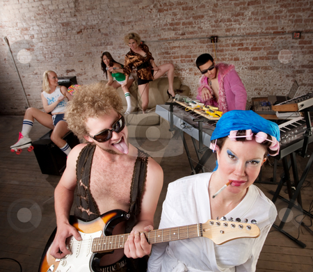 To use this stock image in your creative project, please select the size you need over to the right and click the "Add to Cart" button.
Your downloaded image will come with the Cutcaster watermark removed so don’t worry about the watermark you see on this page. 1970s Disco Music Party stock photo, Young guitarist teasing woman in curlers at a 1970s Disco Music Party by Scott Griessel