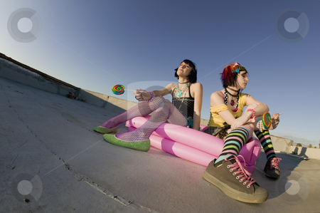 To use this stock image in your creative project, please select the size you need over to the right and click the "Add to Cart" button.
Your downloaded image will come with the Cutcaster watermark removed so don’t worry about the watermark you see on this page. Girsl on a roof in a plastic pool stock photo, Fisheye shot of girls in brightly colored clothing in a plastic pool on a roof with sunglasses and lollipops by Scott Griessel