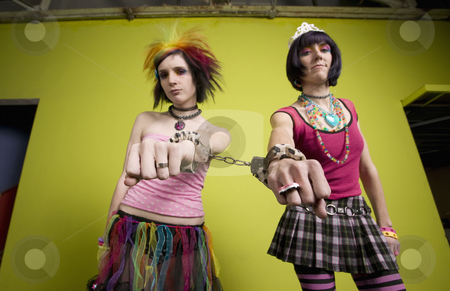 To use this stock image in your creative project, please select the size you need over to the right and click the "Add to Cart" button.
Your downloaded image will come with the Cutcaster watermark removed so don’t worry about the watermark you see on this page. Young punk women linked by handcuffs stock photo, Wide angle of young punk women in front of a green wall linked by handcuffs by Scott Griessel
