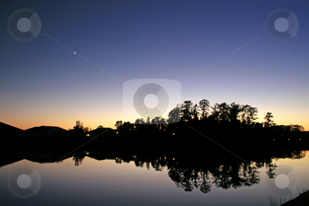 To use this stock image in your creative project, please select the size you need over to the right and click the "Add to Cart" button.
Your downloaded image will come with the Cutcaster watermark removed so don’t worry about the watermark you see on this page. Sunset Reflections stock photo, A Sunset, Moon, Trees, Lake and Silhouettes by Lucy Clark