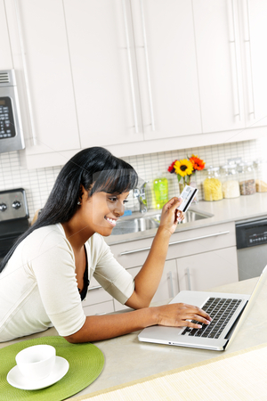 To use this stock image in your creative project, please select the size you need over to the right and click the "Add to Cart" button.
Your downloaded image will come with the Cutcaster watermark removed so don’t worry about the watermark you see on this page. Woman shopping online at home stock photo, Smiling black woman online shopping using computer and credit card in kitchen by Elena Elisseeva