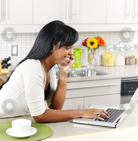 To use this stock image in your creative project, please select the size you need over to the right and click the "Add to Cart" button.
Your downloaded image will come with the Cutcaster watermark removed so don’t worry about the watermark you see on this page. Woman using computer in kitchen stock photo, Smiling black woman using computer in modern kitchen interior by Elena Elisseeva