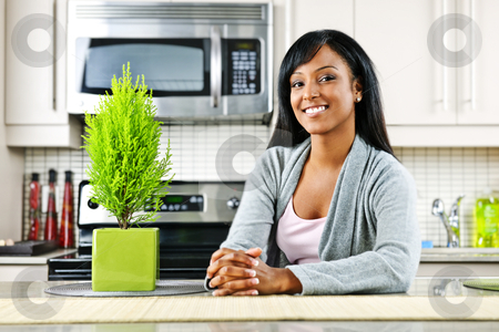 To use this stock image in your creative project, please select the size you need over to the right and click the "Add to Cart" button.
Your downloaded image will come with the Cutcaster watermark removed so don’t worry about the watermark you see on this page. Young woman in kitchen stock photo, Smiling black woman in modern kitchen interior by Elena Elisseeva
