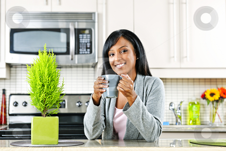 To use this stock image in your creative project, please select the size you need over to the right and click the "Add to Cart" button.
Your downloaded image will come with the Cutcaster watermark removed so don’t worry about the watermark you see on this page. Woman in kitchen with coffee cup stock photo, Smiling black woman holding coffee mug in modern kitchen interior by Elena Elisseeva