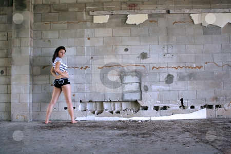 To use this stock image in your creative project, please select the size you need over to the right and click the "Add to Cart" button.
Your downloaded image will come with the Cutcaster watermark removed so don’t worry about the watermark you see on this page. Sexy Brunette at a Block Wall (5) stock photo, A lovely young brunette wearing black boy shorts with white patterns and a white T-shirt with black stripes, stands with her back to the camera in front of an old, dilapidated block wall. Wide shot with plenty of room for adding text, artwork, graffiti, etc. by Carl Stewart